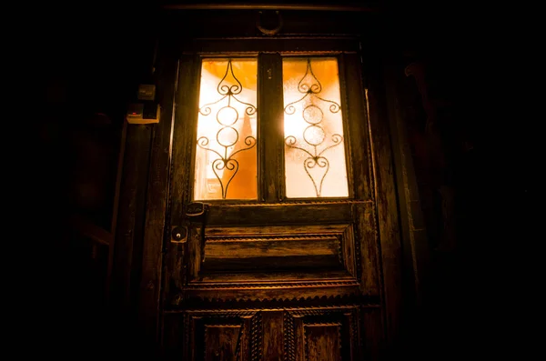 Sylwetka nieznanego cienia figura na starych drewnianych drzwiach przez zamknięte szklane drzwi. Sylwetka człowieka przed oknem w nocy. — Zdjęcie stockowe