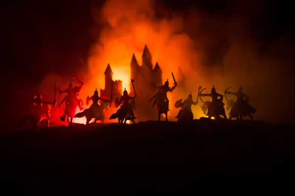 Mittelalterliche Kampfszene mit Kavallerie und Infanterie. Silhouetten von Figuren als separate Objekte, Kampf zwischen Kriegern auf dunkel getöntem Nebelhintergrund mit mittelalterlicher Burg. — Stockfoto