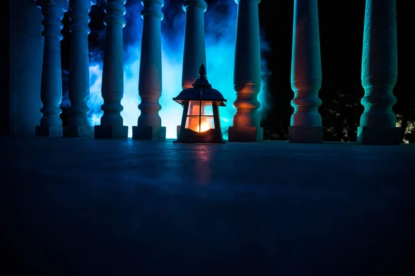 Retro style lantern at night. Beautiful colorful illuminated lamp at the balcony in the garden.