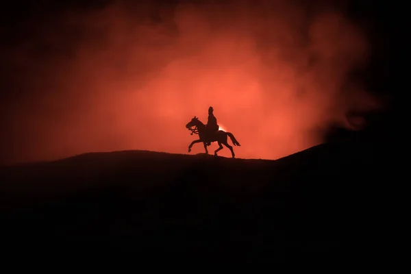 Weltkriegsoffizier (oder Krieger) Reiter zu Pferd mit einem kampfbereiten Schwert und Soldaten auf dunklem, nebelfarbenen Hintergrund. Schlachtszene Schlachtfeld der kämpfenden Soldaten. — Stockfoto