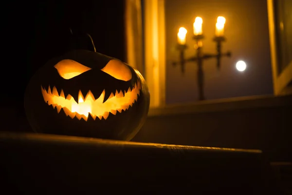 Abóbora de Halloween assustadora na janela mística da casa à noite ou abóbora de Halloween à noite no quarto com janela azul. Símbolo de Halloween em janela . — Fotografia de Stock