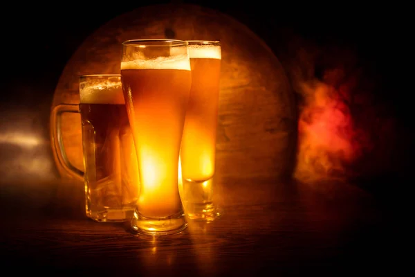 Tvůrčí koncept. Pivní brýle na dřevěném stolku na tmavém, mlhavé pozadí. — Stock fotografie