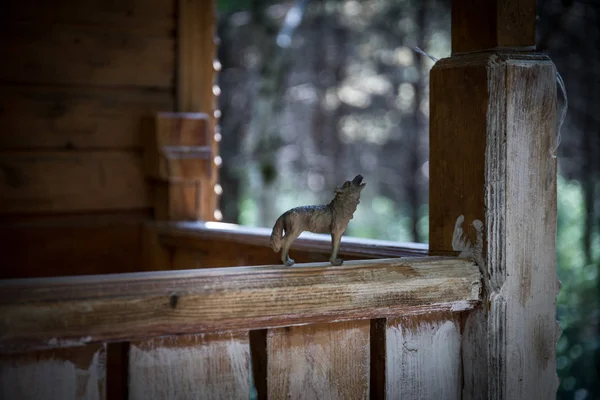 Loup hurlant dans la forêt. Mini figurine de loup debout sur le sol forestier . — Photo