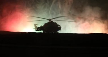 Askeri helikopter çatışma bölgesinden uçmaya hazır silüeti. Gece görüntüleri çöl sisli tonda sırt ile başlayarak helikopter ile dekore edilmiştir. Seçici odak.
