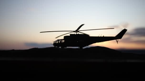Silhouet van militaire helikopter klaar om te vliegen vanaf conflictgebied. Nacht beelden versierd met helikopter starten in woestijn met mistige afgezwakt achtergrondverlichting. Selectieve aandacht. — Stockvideo