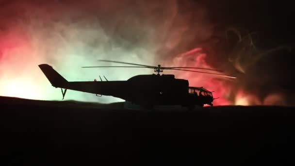 Silhueta de helicóptero militar pronta para voar da zona de conflito. Filmagem noturna decorada com helicóptero começando no deserto com nevoeiro tonificado retroiluminado. Foco seletivo . — Vídeo de Stock