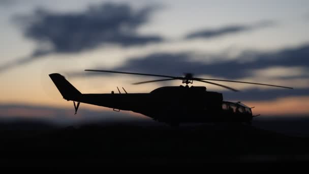 Silhouette of military helicopter ready to fly from conflict zone. Decorated night footage with helicopter starting in desert with foggy toned backlit. Selective focus. — Stock Video