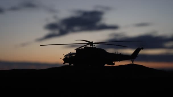 Silueta de helicóptero militar lista para volar desde zona de conflicto. Imágenes nocturnas decoradas con helicóptero comenzando en el desierto con niebla tonificada retroiluminada. Enfoque selectivo . — Vídeo de stock