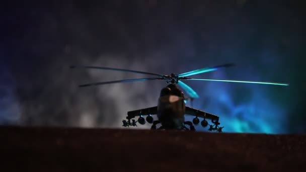 Silueta vojenský vrtulník připravený k letu z oblastí ozbrojených konfliktů. Noční záběry zdobené vrtulník v poušti s mlhavé tónovaný podsvícení. Selektivní fokus. — Stock video