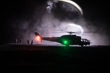 Askeri helikopter çatışma bölgesinden uçmaya hazır silüeti. Gece görüntüleri çöl sisli tonda sırt ile başlayarak helikopter ile dekore edilmiştir. Seçici odak.