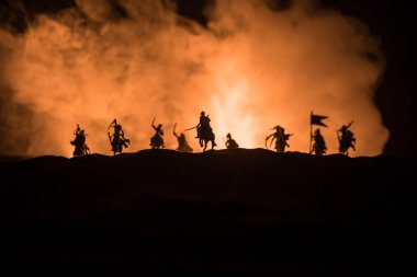 Süvari ve piyade ile ortaçağ savaş sahnesi. Siluetleri şekiller ayrı nesneler olarak mücadele koyu tonda sisli arka plan savaşçılar arasında. Gece çekimi.