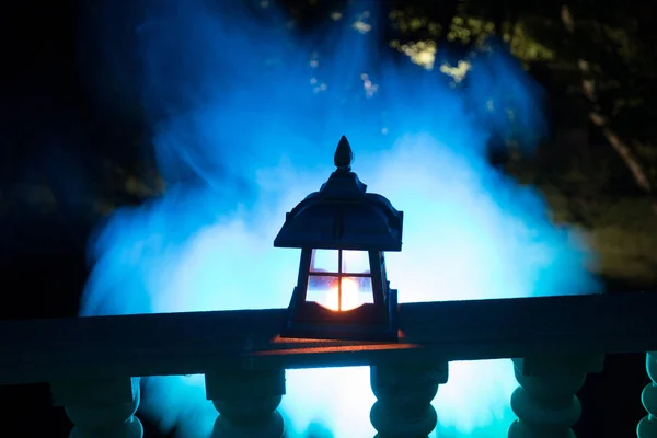 Retro style lantern at night. Beautiful colorful illuminated lamp at the balcony in the garden.