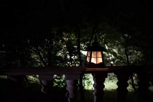 Retro style lantern at night. Beautiful colorful illuminated lamp at the balcony in the garden.