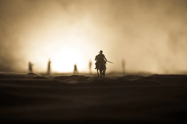 Officier de guerre mondial (ou guerrier) cavalier à cheval avec une épée prête à se battre et des soldats sur un fond sombre et brumeux. Scène de bataille champ de bataille des soldats de combat . — Photo