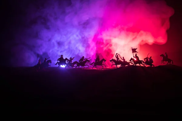 Middeleeuwse slag scène met de cavalerie en infanterie. Silhouetten van figuren als afzonderlijke objecten, strijd tussen krijgers op donker getinte mistige achtergrond. Nachtbeeld. — Stockfoto