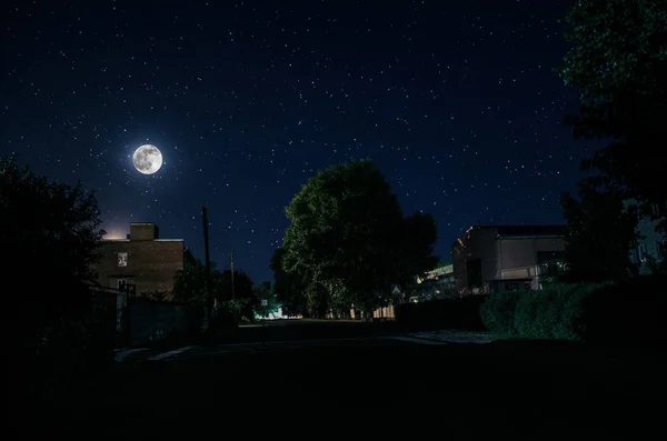 Vollmond über einem ruhigen Dorf in der Nacht. schöne nächtliche Landschaft der Altstadt mit Lichtern. Russland — Stockfoto