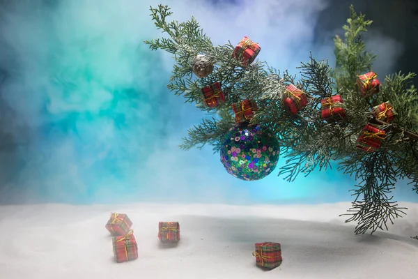 La decoración Navideña - la chuchería sobre la rama del pino con los atributos de fiesta sobre la nieve. Enfoque selectivo —  Fotos de Stock