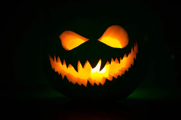 Halloween pumpkin smile and scary eyes for party night. Close up view of scary Halloween pumpkin with eyes glowing inside at black background — Stock Photo, Image