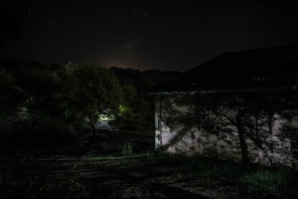 Casa veche cu o fantomă în pădure noaptea sau Casa de groază bântuită abandonată în ceață. Vechea clădire mistică din pădurea copacilor morţi. Copaci noaptea cu luna. Lumini suprarealiste. Horror Halloween concept — Fotografie, imagine de stoc