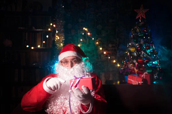 Jultomten sitter i fåtölj på rummet dekorerad för julen. Selektivt fokus — Stockfoto