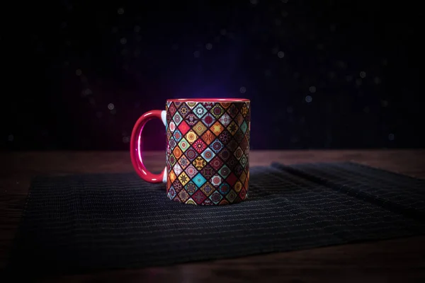 Beautiful eastern style textured ceramic cup of coffee (or tea) with smoke over dark toned background.