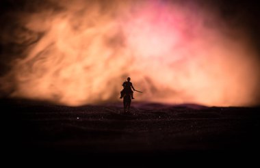 Dünya savaşı subayı (veya savaşçı) bir kılıç savaşmaya hazır ve karanlık sisli tonda arka plan üzerinde asker at üzerinde binici. Savaş alanı savaş alanı savaşan askerler.