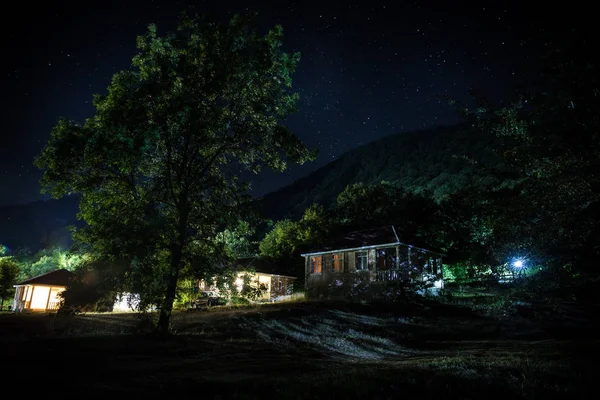 Old house with a Ghost in the forest at night or Abandoned Haunted Horror House in fog. Old mystic building in dead tree forest. Trees at night with moon. Surreal lights. Horror Halloween concept — Stock Photo, Image