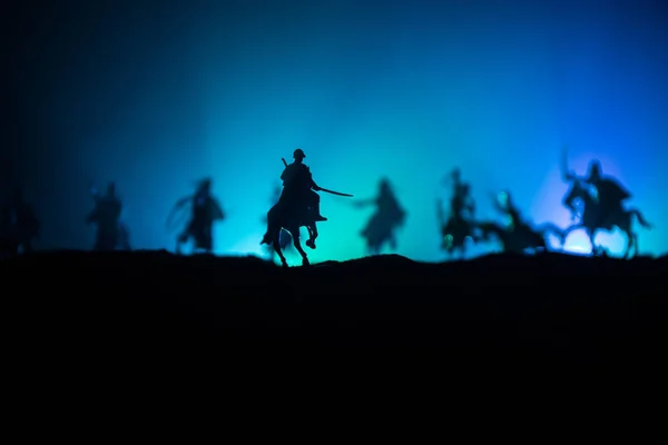 Escena de batalla medieval con caballería e infantería. Siluetas de figuras como objetos separados, lucha entre guerreros sobre fondo de niebla tonificado oscuro. Escena nocturna . — Foto de Stock