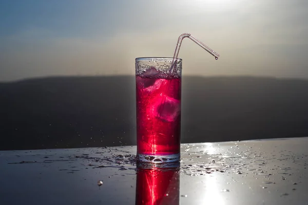 Cooling summer drink concept. Cocktail glasses splashing on sunset. Close up wet glass of cold drink on the terrace.