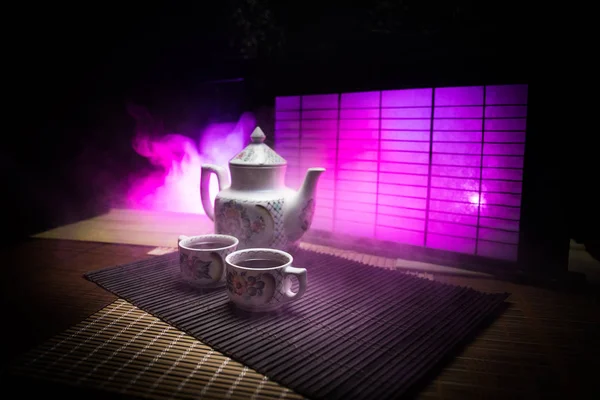Tea concept. Japanese tea ceremony culture east beverage. Teapot and cups on table with bamboo leaves on sunset — Stock Photo, Image