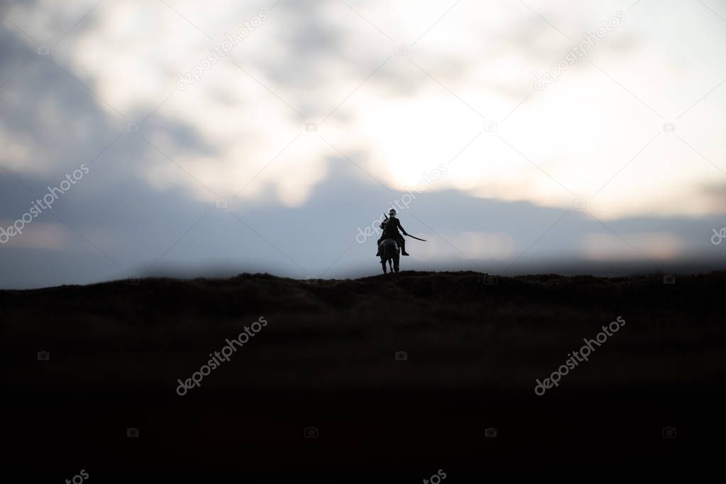 World war officer (or warrior) rider on horse with a sword ready to fight and soldiers on a dark foggy toned background. Battle scene battlefield of fighting soldiers.