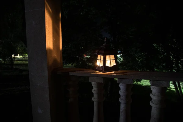 Linterna de estilo retro por la noche. Hermosa lámpara iluminada de colores en el balcón en el jardín . —  Fotos de Stock