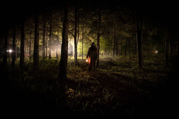 Luz estranha em uma floresta escura à noite. Silhueta de pessoa de pé na floresta escura com luz. Noite escura na floresta na hora do nevoeiro. Surreal noite floresta cena . — Fotografia de Stock