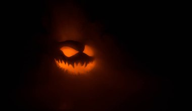 Cadılar Bayramı balkabağı gülümseme ve parti gece için korkutucu gözleri. Siyah arka planda parlayan gözleri ile korkunç Halloween kabak görünümüne yakın