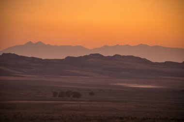 Gün batımında Azerbaycan 'daki siluet dağlarının ve yalnız ağaçların manzarası. Sheki