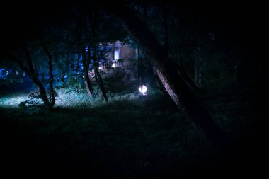 Korku Cadılar Bayramı konsepti. Geceleri ormanda eski yağ lambası yakmak. Kabus sahnesinin gece manzarası.