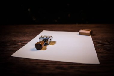 Koyu tonda sisli arka plan ile ahşap masa üzerinde kauçuk tarih damgası yakından görünümü.