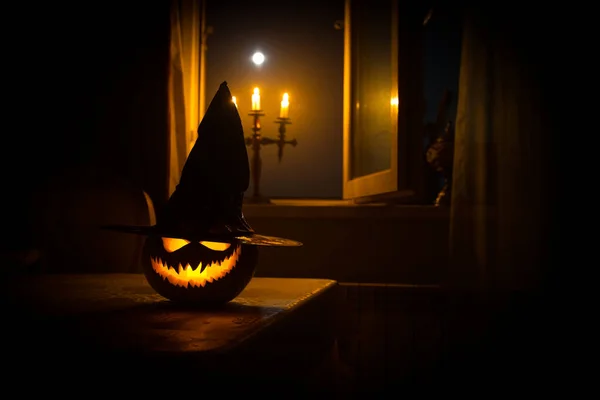 Enge Halloween pompoen in het venster van de mystieke huis bij nacht of halloween pompoen in nacht op kamer met blauwe venster. Symbool van halloween in venster. — Stockfoto