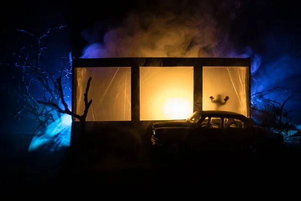 Old house with a Ghost in the forest at night. Horror silhouette at the window. Old building in forest. Surreal lights. Horror Halloween concept