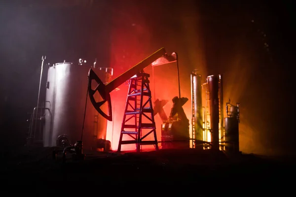 Decoración de obra. Bomba de aceite y plataforma de aceite máquinas industriales de energía para el petróleo por la noche con niebla y contraluz. Fábrica de refino de petróleo. Concepto industrial energético. Enfoque selectivo — Foto de Stock