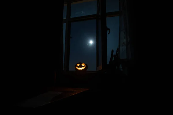 La zucca di Vigilia d'Ognissanti spaventosa nella finestra di casa mistica di notte o la zucca di Halloween in notte su camera con finestra azzurra. Simbolo di Halloween in finestra . — Foto Stock