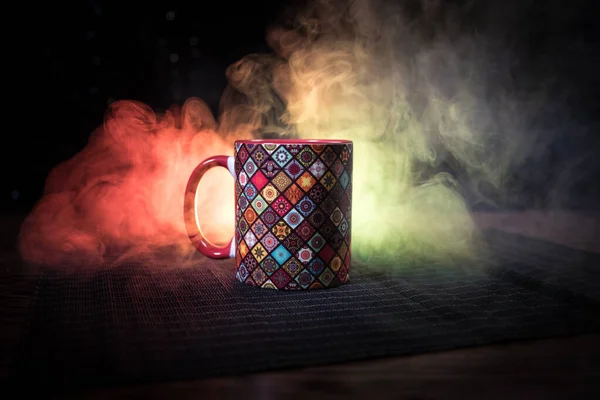 Beautiful eastern style textured ceramic cup of coffee (or tea) with smoke over dark toned background.