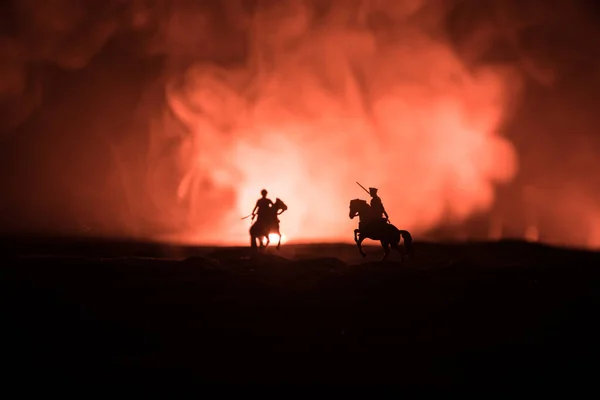 Ο παγκόσμιος αξιωματικός του πολέμου (ή πολεμιστής) αναβάτης στο άλογο με ένα σπαθί έτοιμο να πολεμήσει και στρατιώτες σε ένα σκοτεινό φόντο με θολή απόχρωση. Μάχη σκηνή μάχης των στρατιωτών της μάχης. — Φωτογραφία Αρχείου