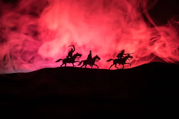 Escena de batalla medieval con caballería e infantería. Siluetas de figuras como objetos separados, lucha entre guerreros sobre fondo de niebla tonificado oscuro. Escena nocturna . — Foto de Stock