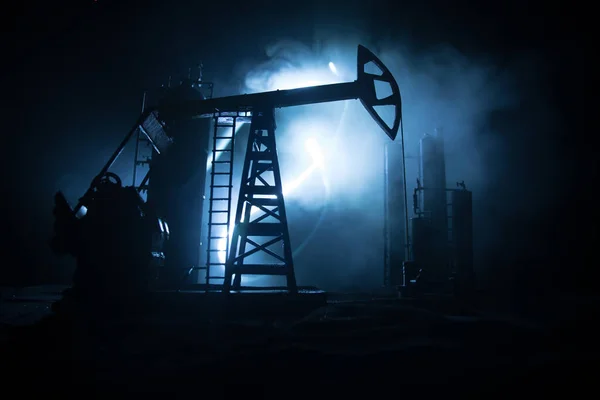 Dekoracja dzieł sztuki. Pompy oleju i platformy wiertnicze energii maszyn przemysłowych do ropy naftowej w nocy z mgły i podświetlenia. Fabryka rafinacji ropy. Koncepcja energetyczna. Skupienie selektywne — Zdjęcie stockowe