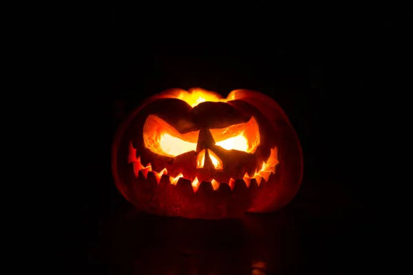 Nahaufnahme von gruseligen Halloween-Kürbissen mit innen leuchtenden Augen vor schwarzem Hintergrund. Selektiver Fokus — Stockfoto