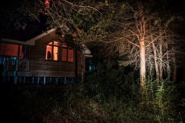 Старый дом с призраком в лесу ночью или заброшенный Дом с привидениями в тумане. Старое мистическое здание в мертвом лесу. Деревья ночью с луной. Сюрреалистичный свет. Концепция Хэллоуина ужасов — стоковое фото