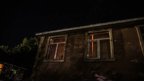 Geceleri ormanda bir hayaletin olduğu eski bir ev ya da sis içinde terk edilmiş bir korku evi. Ölü ağaç ormanındaki eski mistik bina. Geceleri aylı ağaçlar. Gerçeküstü ışıklar. Korku Cadılar Bayramı konsepti — Stok fotoğraf