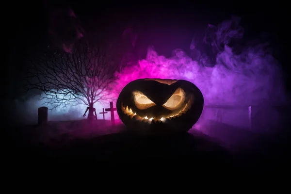 Eng uitzicht op zombies op het kerkhof 's nachts. Dode boom en griezelige bewolkte lucht met mist. Horror Halloween concept met gloeiende pompoen. — Stockfoto