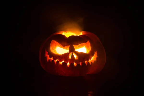 Vista de perto da abóbora de Halloween assustadora com olhos brilhando dentro no fundo preto. Foco seletivo — Fotografia de Stock